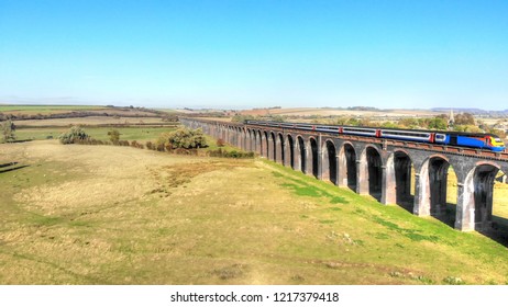 Aerial View Of A Passenger Train, Travelling Over A Viaduct.