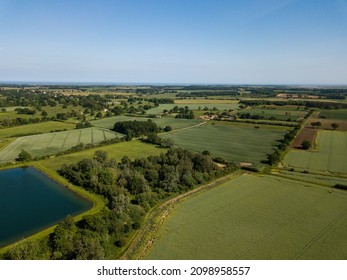 Aerial view of a patchwork of farm fields in the Suffolk countryside with a large reservoir in the foreground