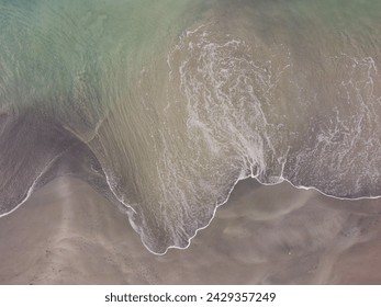 Aerial view of patterns in the breaking waves on a sandy beach