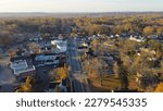 Aerial view Penfield town with local business, residential houses, churches along Five Mile Line Street lush green East Rochester in distant background, Upstate New York, USA. Colorful autumn leaves