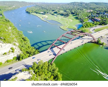 Aerial view Pennybacker Bridge or 360 Bridge, a landmark in Austin, Texas, US. Variety of high speed boat, yacht, jet ski on Colorado River and car traffic. Downtown skyscrapers are on the far left.