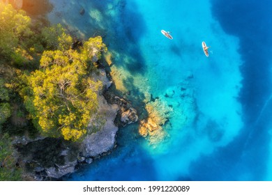 Aerial view of people on floating sup boards on blue sea, rocks, trees at sunset in summer. Blue lagoon, Oludeniz, Turkey. Tropical landscape. Kayaks on clear water. Active travel. Top view of canoe - Powered by Shutterstock