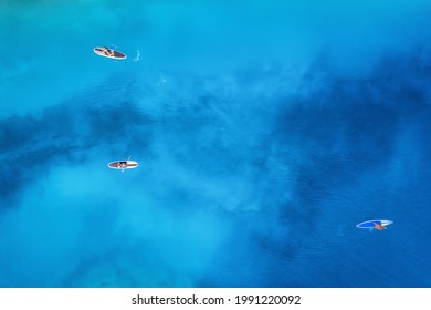 Aerial view of people on floating sup boards on blue sea at sunset in summer. Blue lagoon, Oludeniz, Turkey. Tropical landscape. Kayaks on clear water. Active travel. Top view of canoe. Sport