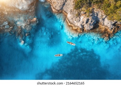 Aerial view of people on floating kayaks on blue sea, rocky coast, trees at sunset in summer. Blue lagoon, Oludeniz, Turkey. Tropical landscape. Sup boards on clear water. Top view of canoe. Tourism - Powered by Shutterstock