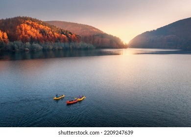 Aerial view of people on floating colorful boats on blue lake in mountains with red forest at sunset in autumn. River in carpathian mountains in fall in Ukraine. Landscape. Top view of canoe. Travel - Powered by Shutterstock