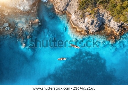 Aerial view of people on floating kayaks on blue sea, rocky coast, trees at sunset in summer. Blue lagoon, Oludeniz, Turkey. Tropical landscape. Sup boards on clear water. Top view of canoe. Tourism