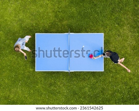 Aerial view people playing ping pong match outdoor. Top view two boys playing table tennis on a green grass lawn. Aerial view outdoor sport
