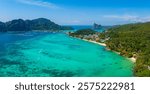 Aerial view of Phi Phi Islands in Thailand, showcasing turquoise waters, lush green hills, limestone formations, sandy beaches, and small boats.