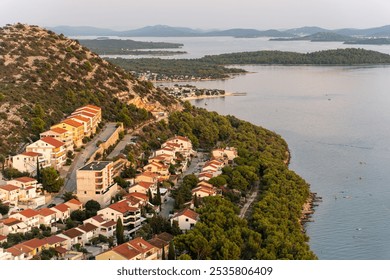 Aerial view of picturesque coastal town at sunset with red-roofed houses surrounded by lush green forest along the Adriatic Sea. High quality photo - Powered by Shutterstock