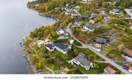 Aerial view of a picturesque coastal village with houses, green fields, and a marina. The landscape features residential homes, trees, and a body of water, showcasing the beauty of rural living. - Powered by Shutterstock