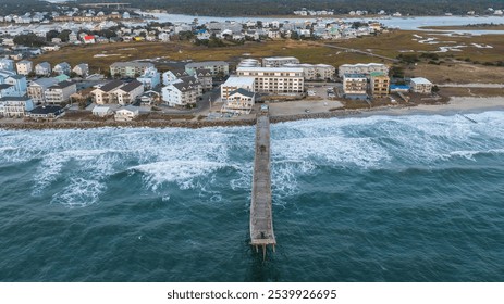 Aerial view of the pier at Carolina Beach, North Carolina, stretching into the Atlantic Ocean, with surrounding coastal homes and marshland in the background. - Powered by Shutterstock