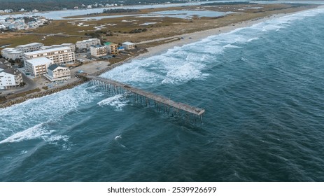 Aerial view of the pier at Carolina Beach, North Carolina, stretching into the Atlantic Ocean, with surrounding coastal homes and marshland in the background. - Powered by Shutterstock