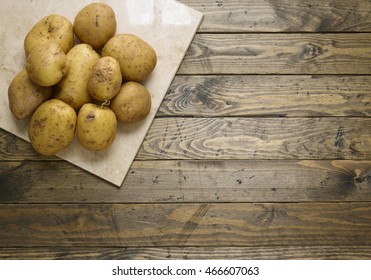 An Aerial View Of A Pile Of Uncooked Baking Potatoes On A Rustic Wooden Kitchen Counter Background