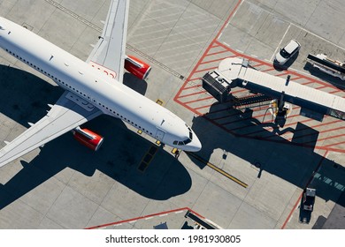 Aerial view of plane. Airplane in front of the passenger boarding bridge from airport terminal.