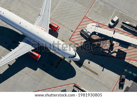 Aerial view of plane. Airplane in front of the passenger boarding bridge from airport terminal.
