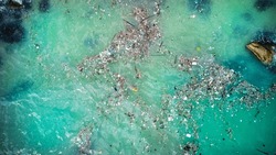 Aerial View Of Plastic Pollution And Debris Floating In Vibrant Turquoise Ocean Waters, Highlighting Environmental Issues