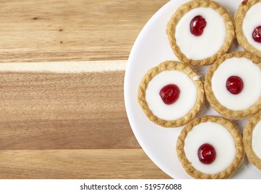 Aerial View Of A Plate Full Of Freshly Baked Bakewell Tarts On A Wooden Kitchen Counter Top Background With Blank Space At Side