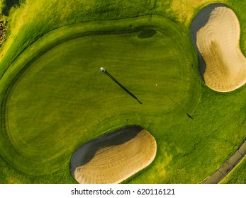 Aerial view of players on a green golf course. Golfer playing on putting green on a summer day.
