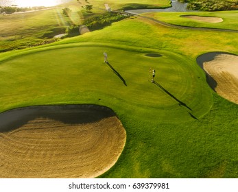 Aerial view of players on a green golf course. Golfer playing on putting green on a summer day. - Powered by Shutterstock