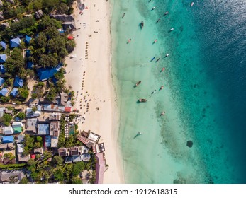 Aerial view of pool, umbrellas, sandy beach with green Palm trees. Coast of Indian ocean at sunset in summer. Zanzibar, Africa. Top view. Landscape with azure water, parasols, palm trees. Luxury