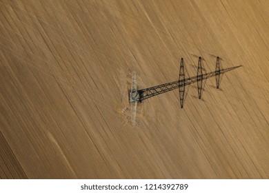 Aerial View Of Power Line In A Agricultural Plowed Field Prepared For Planting. Shoot From Drone Directly Above