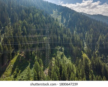 Aerial View Of Power Line Through Alpine Forest In Switzerland. Electric Current Distribution With Power Grid.