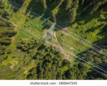 Aerial View Of Power Line Through Alpine Forest In Switzerland. Electric Current Distribution With Power Grid.