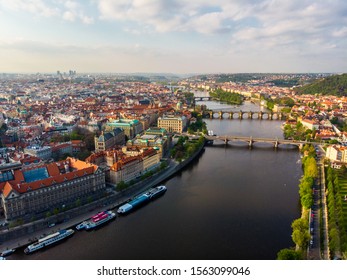 Aerial view of Prague city with Vltava river flowing along it, and multiple bridges crossing the river. One of the bridges is the famous St Charles Bridge. 