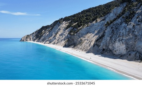 Aerial view of a pristine beach with turquoise water and a rugged cliffside under a clear blue sky in Lefkada, Greece - Powered by Shutterstock