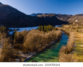 Aerial view of a pristine river winding through a picturesque valley surrounded by forests and fields, with rolling hills in the background - Powered by Shutterstock