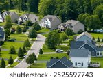 Aerial view of private residential houses in rural suburban sprawl area in Rochester, New York. Upscale suburban homes with large backyards and green grassy lawns in summer season