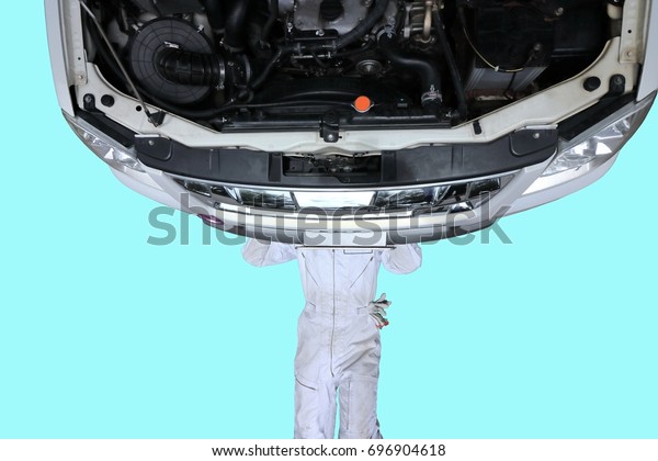 Aerial view of professional young mechanic lying\
down and repairing under car on blue isolated background.\
Maintenance people\
concept.