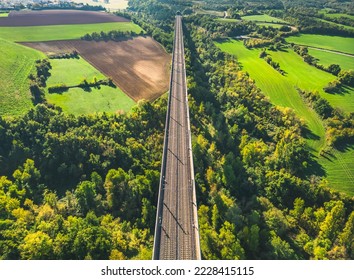 Aerial view of the railroad tracks for high-speed trains on the flyover. Panoramic autumn view of the surrounding fields and forests and the surrounding mountains. - Powered by Shutterstock