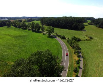 aerial view of a red car on a country road between Agricultural fields in Germany