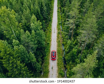 Aerial View Of Red Car With A Roof Rack On A Green Summer Forest Country Road In Finland