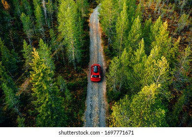 Aerial view of red car for traveling with a roof rack on a country road in Finland