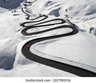 Aerial view of a red car traversing Julier Pass in the Swiss Alps