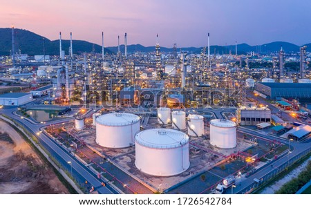 Aerial view Refinery and oil storage tanks at dusk and night. Petrochemical and energy oil industries.
