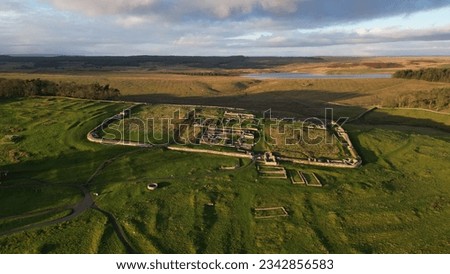 An aerial view of the remains of an auxiliary fort on Hadrian's Wall,  Housesteads Roman Fort, in Northumberland, England,in a middle of a green field