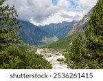 Aerial view of remote village Valbona surrounded by majestic mountain massif Kolata, Albanian Alps (Accursed Mountains), Valbone Valley National Park, Northern Albania. Luxury alpine resort hotels