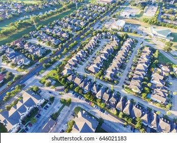 Aerial view of residential houses neighborhood and apartment building complex at sunset. Tightly packed homes, driveway surrounds green tree flyover in Houston, Texas, US. Suburban housing development