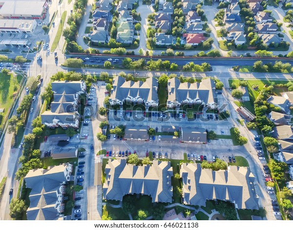 Aerial view of residential houses\
neighborhood and apartment building complex at sunset. Tightly\
packed homes, driveway surrounds green tree flyover in Houston,\
Texas, US. Suburban housing\
development