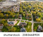 Aerial view of residential neighborhood in Northfield, IL. Lots of trees starting to turn autumn colors. Large residential homes. Meandering streets with large trees.