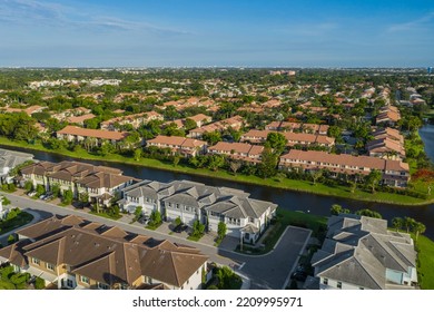 Aerial View Of Residential Neighborhood, Street, Trees, Cars, Blue Sky And Cityscape