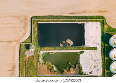 Aerial View Of Retention Basins, Wet Pond, Wet Detention Basin Or Stormwater Management Pond Near Biogas Bio-gas Plant From Pig Farm. Artificial Pond With Vegetation Around Perimeter.