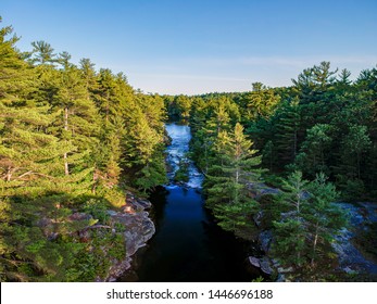 Aerial View Of A River Surrounded By Rugged Shore With Rocks And Cliffs And Coniferous Forest. Ontario, Canada, North America. Shot With Drone On Sunny Summer Day. Hiking, Camping, Kayaking Concept.