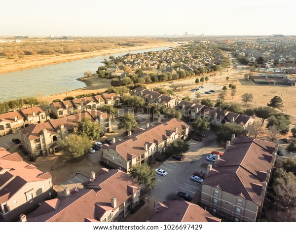 Aerial view riverside\
apartment buildings complex and residential houses neighborhood in\
Irving, Texas, USA.