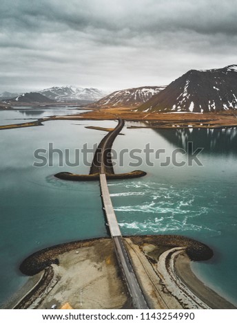 Aerial view of road 1 in iceland with bridge over the sea in Snaefellsnes peninsula with clouds, water and mountain in background