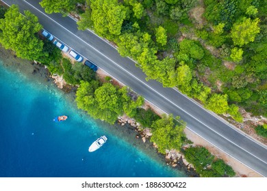 Aerial View Of Road In Beautiful Green Forest And Sea Coast At Sunset In Spring. Colorful Landscape With Cars On Roadway, Boat, Blue Water, Trees In Summer. Top View Of Highway In Croatia. Travel