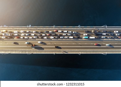 Aerial View Of Road Bridge Across River With Heavy Traffic Jam In One Direction. Rush Hour With Mash And Overloading Of Road Infrastructure. Resolving Of Car Traffic Jam